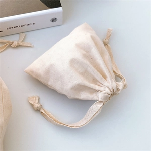 Detailed close-up of a beige cotton drawstring pouch with natural fabric texture