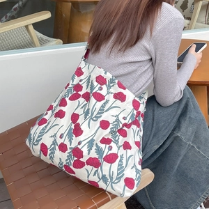 Floral canvas tote bag with red poppy prints shown in a cozy outdoor cafe setting