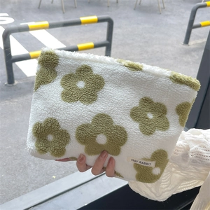 Close-up of fluffy floral makeup bag with green flower patterns and brand label