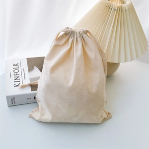 Close-up of natural cotton linen drawstring bag with textured fabric on a white desk