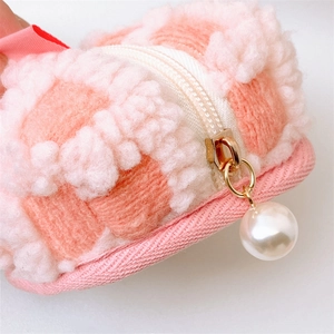 Close-up of pink waffle texture plush coin purse with pearl zipper pull detail