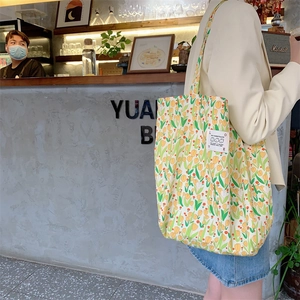 Gros plan du motif tulipes jaunes et de l'écusson sur le grand sac cabas en toile