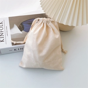 Detailed view of cream cotton drawstring bag texture on a minimalist background