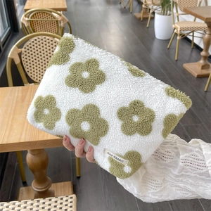 Detail of plush floral pouch in green and white teddy fleece held in a cozy cafe setting