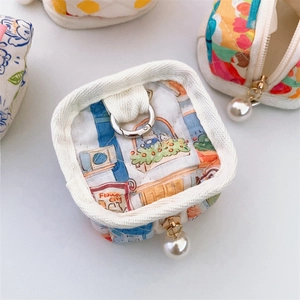 Detailed close-up of quilted fabric earphone cases with city cat patterns and pearl charms