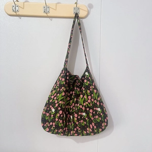 Close-up of black floral tote bag featuring pink tulip patterns and canvas texture