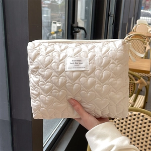 Detailed view of heart-quilted pattern and fabric label on a cream makeup bag