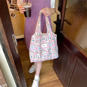 Sac fourre-tout en toile à motif tulipes avec bandoulière tenu dans un décor décontracté