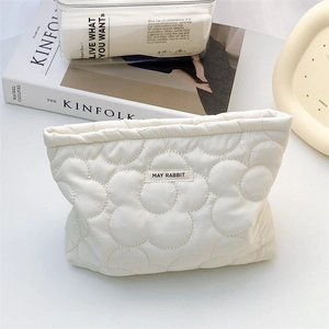 Off-white quilted storage bag with large flower pattern and minimalist brand label