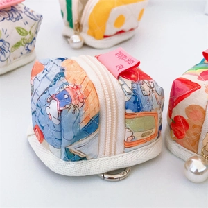 Detail of quilted cotton earphone pouch with cartoon prints and a pearl pendant