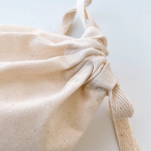 Macro detail of natural cotton drawstring bag showing stitching and canvas texture