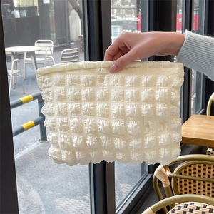 Detailed texture of off-white bubble puffer bag held by a model in an outdoor setting