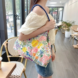 Dettaglio della borsa tote floreale con manici in corda blu e logo del marchio