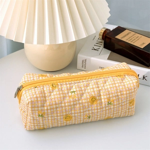 Detail of yellow checkered quilted pencil case with cherry print on a cozy desktop