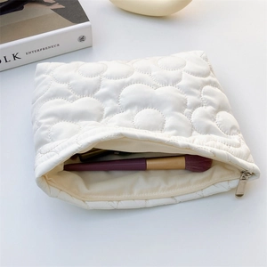 Detailed close-up of quilted floral pattern on cream cotton makeup bag with smooth zipper