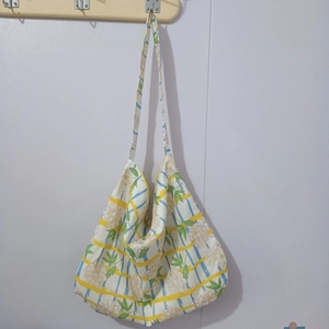Front view of large floral canvas tote bag with yellow and blue stripes hanging on wall