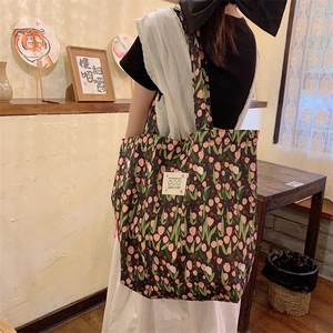 Détail du sac cabas en toile à fleurs avec tulipes roses et étiquette de marque en tissu