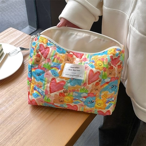 Detailed view of quilted makeup bag featuring colorful cartoon prints and a zipper closure