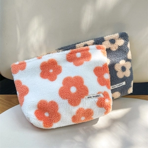 Close-up of floral plush makeup bags showing soft sherpa texture and zipper detail