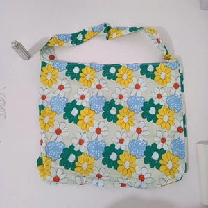 Detail of floral canvas tote bag with yellow and blue daisy patterns on white background