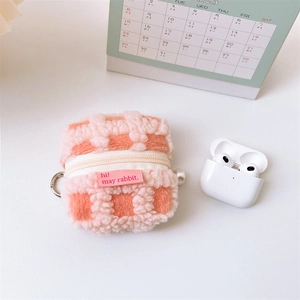 Macro detail of plush checkered waffle texture with zipper and pearl charm on earbud pouch