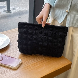 Handheld view of a black bubble textured puffy makeup bag with a secure zipper closure