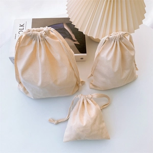 Detailed set of three beige cotton drawstring storage bags in various sizes for organization
