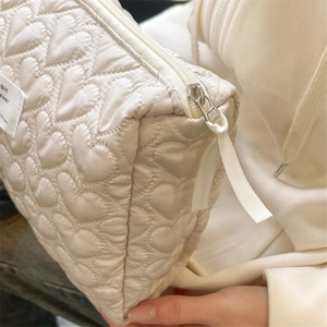 Detail of heart quilted stitching and fabric texture on cream makeup organizer bag