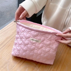 Detail of pink quilted cosmetic bag featuring heart patterns and MAY RABBIT brand label