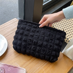 Flat lay of black bubble texture cosmetic bag on a wooden table for daily storage