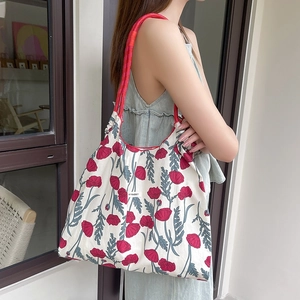 Dettaglio borsa shopper in tela floreale con manici in corda rossa indossata