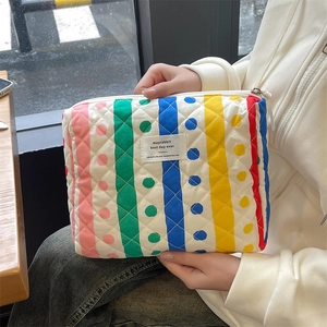 Close-up of quilted colorful striped fabric pouch with diamond stitching and label