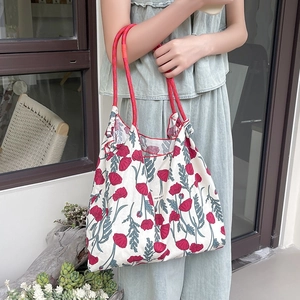 Borsa tote in tela floreale con manici in corda rossa indossata da una modella