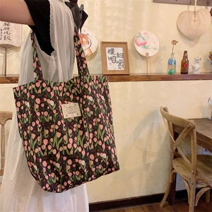 Gros plan détaillé d'un grand sac cabas noir en toile à motif de tulipes roses