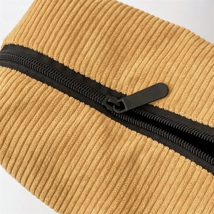 Macro view of high-density corduroy fabric and black zipper on yellow cosmetic bag