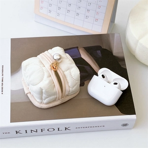 Quilted cream earphone case with pearl detail on Kinfolk magazine background
