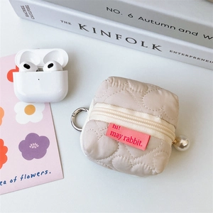 Détail de la mini pochette cœur matelassée beige avec perle et mousqueton en métal