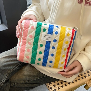 Macro detail of quilted striped floral cosmetic bag showing soft cotton texture and fabric label