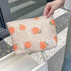 Detail of floral peach jacquard fabric with textured relief on beige cosmetic bag