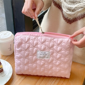 Close-up of pink quilted heart pattern and brand label on a large cosmetic storage bag
