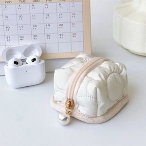 Detail of quilted floral earphone case with elegant pearl zipper and soft texture