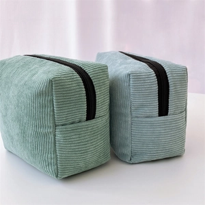 Detailed close-up of corduroy makeup bags in mint green and light blue with zipper