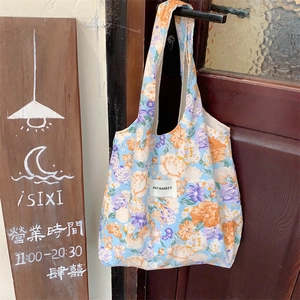 Détail du sac cabas en toile à fleurs avec motifs de tulipes suspendu à une porte en bois