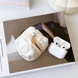 Quilted floral earphone pouch with large pearl zipper on a stylish lifestyle magazine