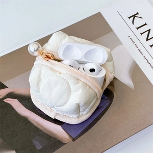 Detailed shot of white quilted fabric earphone case with large pearl charm on Kinfolk magazine