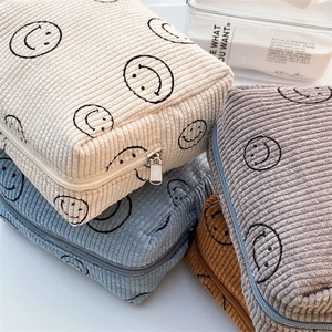 Detailed corduroy texture and smiley face patterns on multi-color cosmetic pouches