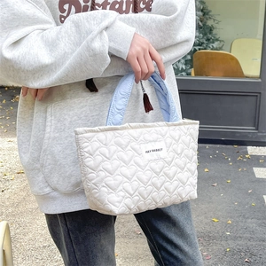 Detail of white heart quilted tote bag with light blue handles in a lifestyle street setting