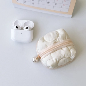 Close-up of quilted cream earphone case with gold zipper and pearl pendant detail