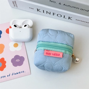 Détail pochette bleue matelassée à motifs cœurs avec fermeture verte et breloque perle
