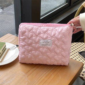 Pink quilted heart makeup bag with large capacity for travel on wooden background